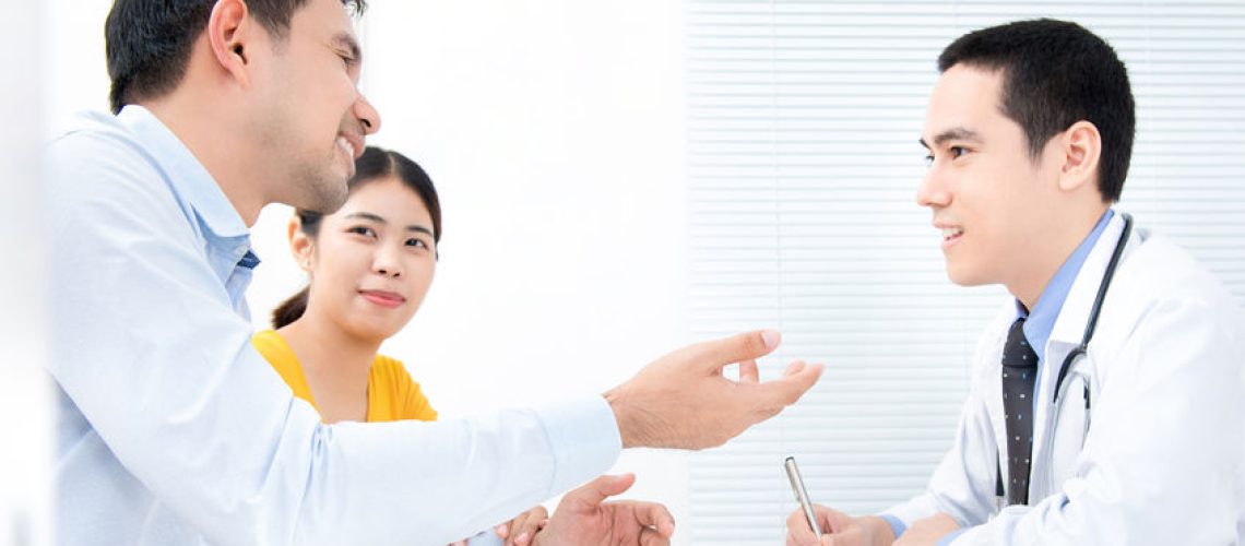Young Asian couple talking with doctor