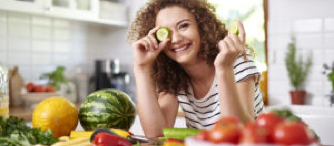 Woman holding a slice of cucumber