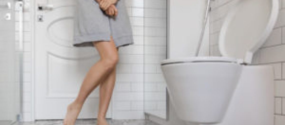 Woman with prostate problem in front of toilet bowl. Lady with hands holding People wants to pee - urinary incontinence concept