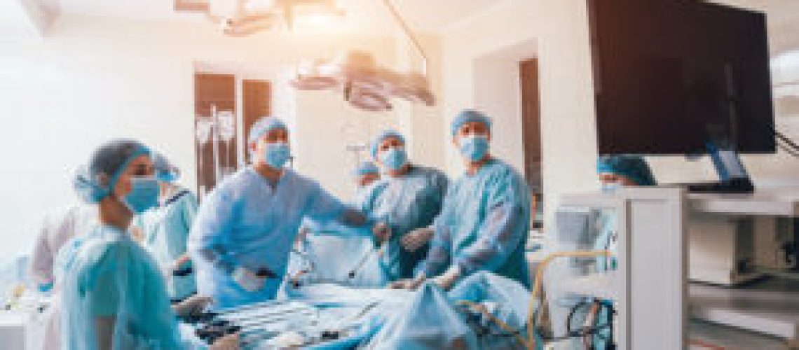 Process of gynecological surgery operation using laparoscopic equipment. Group of surgeons in operating room with surgery equipment. Background